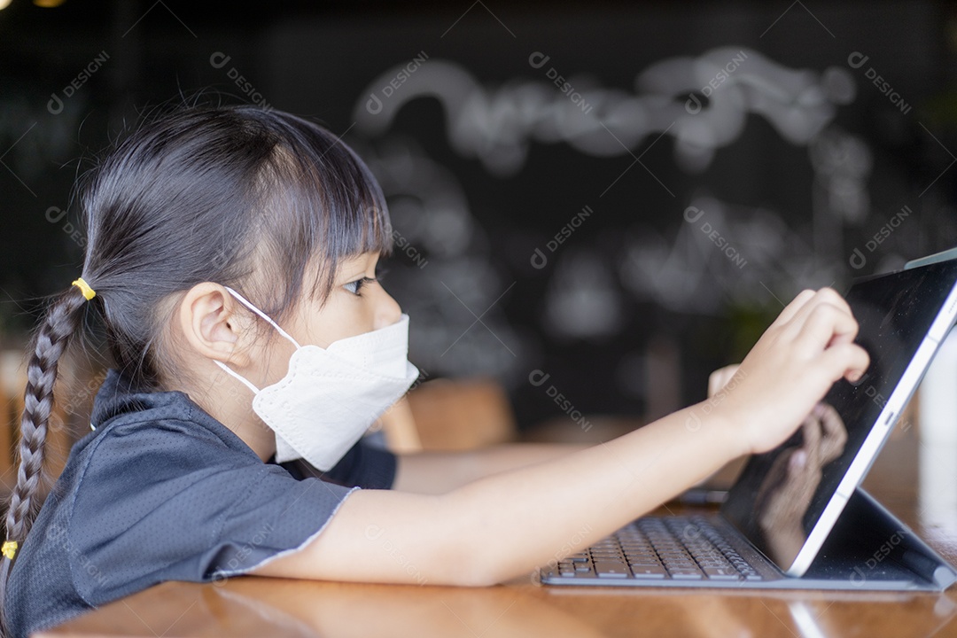Menina asiática feliz olha para tablet na mesa