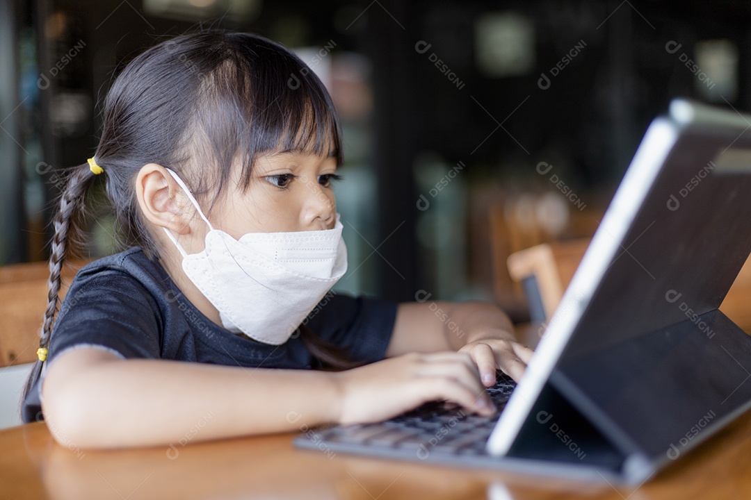 Menina asiática feliz olha para tablet na mesa