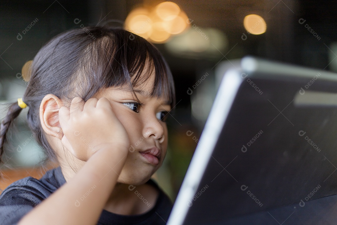 Menina asiática feliz olha para tablet na mesa