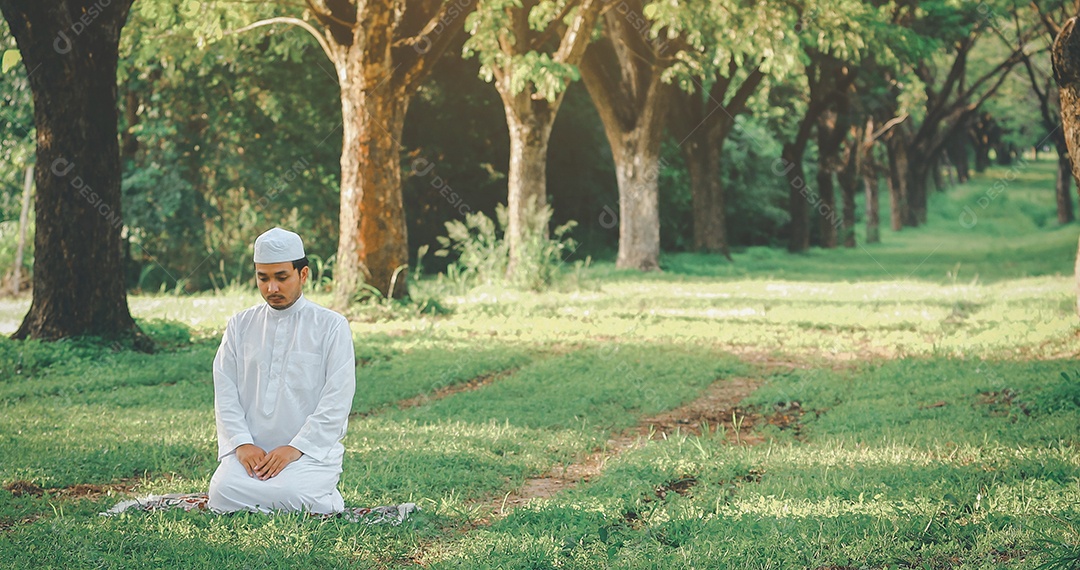 Homem muçulmano religioso tradicional kandura orando ao ar livre em raios de sol de ambiente de natureza tranquila.