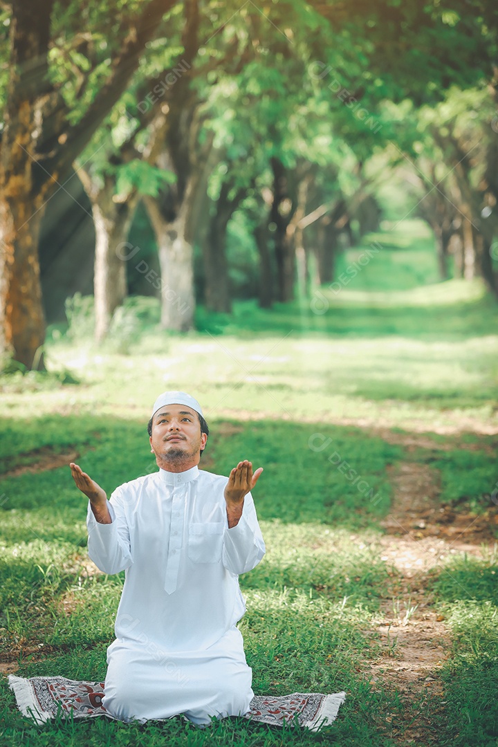 Homem muçulmano religioso tradicional kandura orando ao ar livre em raios de sol de ambiente de natureza tranquila.
