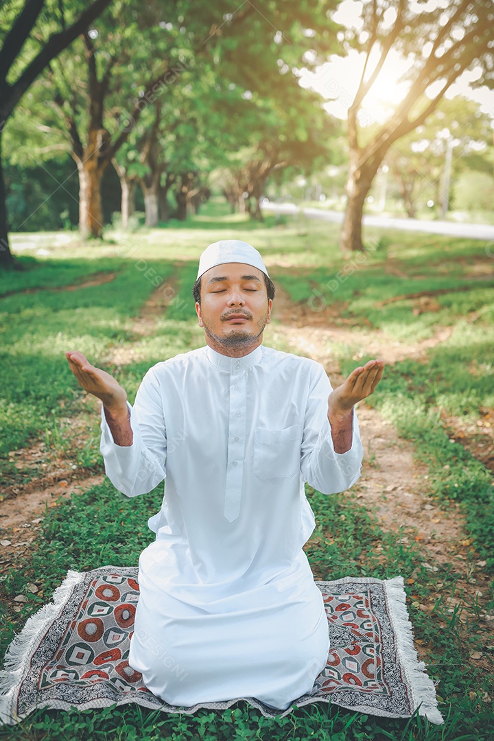 Homem muçulmano religioso tradicional kandura orando ao ar livre em raios de sol de ambiente de natureza tranquila.