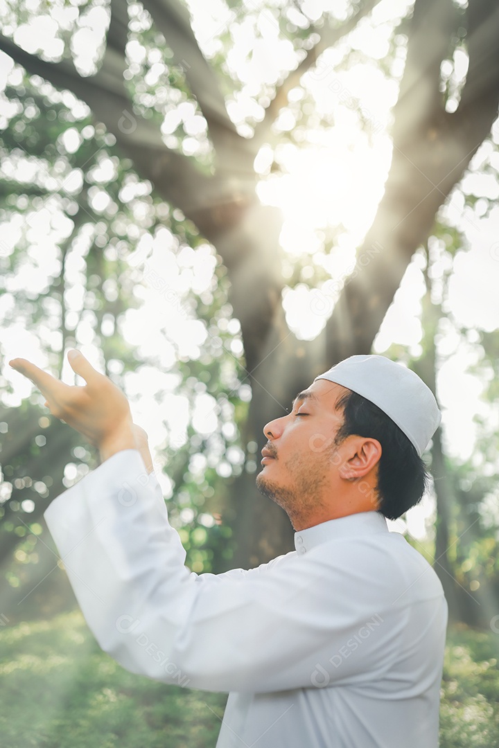 Homem muçulmano religioso tradicional kandura orando ao ar livre em raios de sol de ambiente de natureza tranquila.