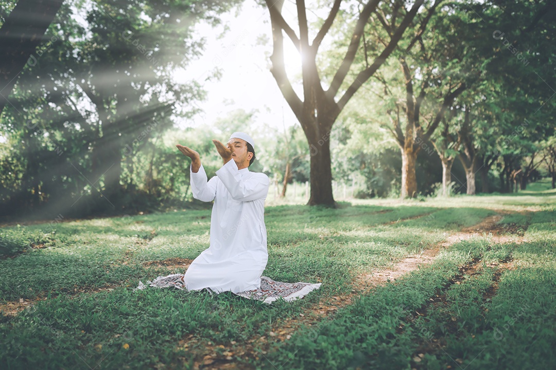Homem muçulmano religioso tradicional kandura orando ao ar livre em raios de sol de ambiente de natureza tranquila.