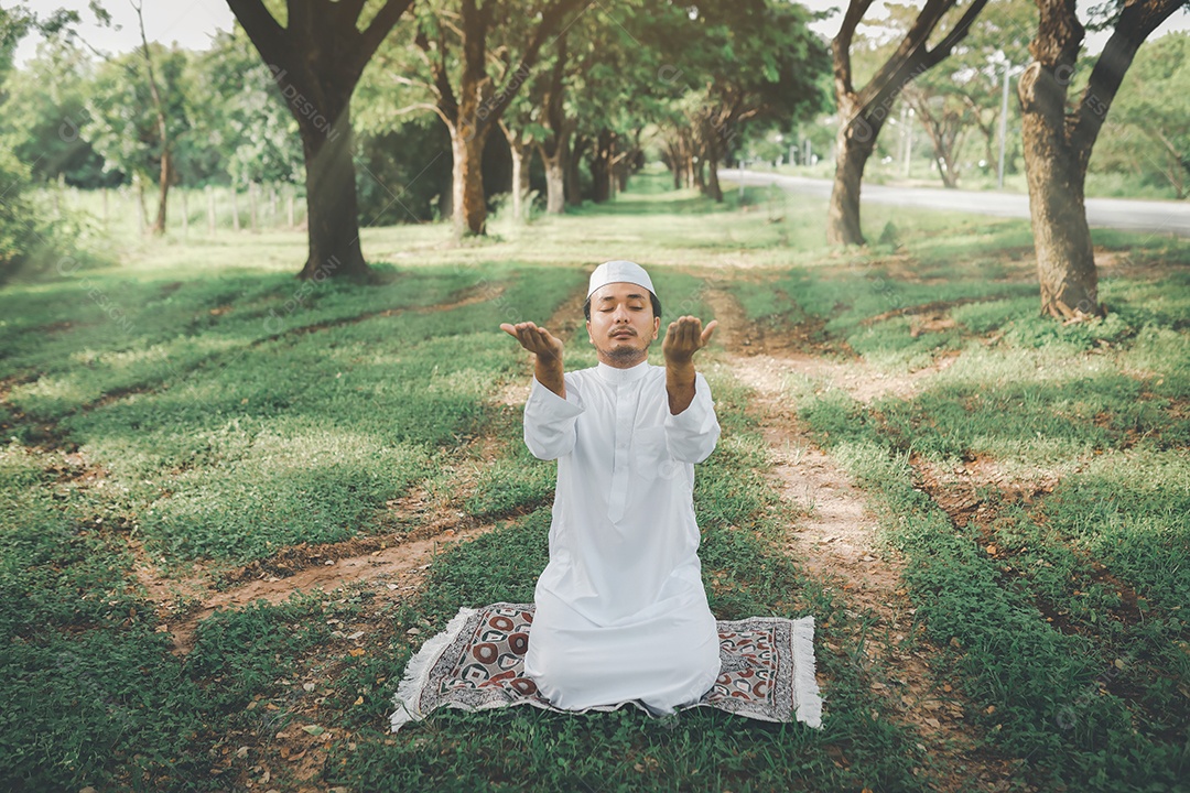 Homem muçulmano religioso tradicional kandura orando ao ar livre em raios de sol de ambiente de natureza tranquila.