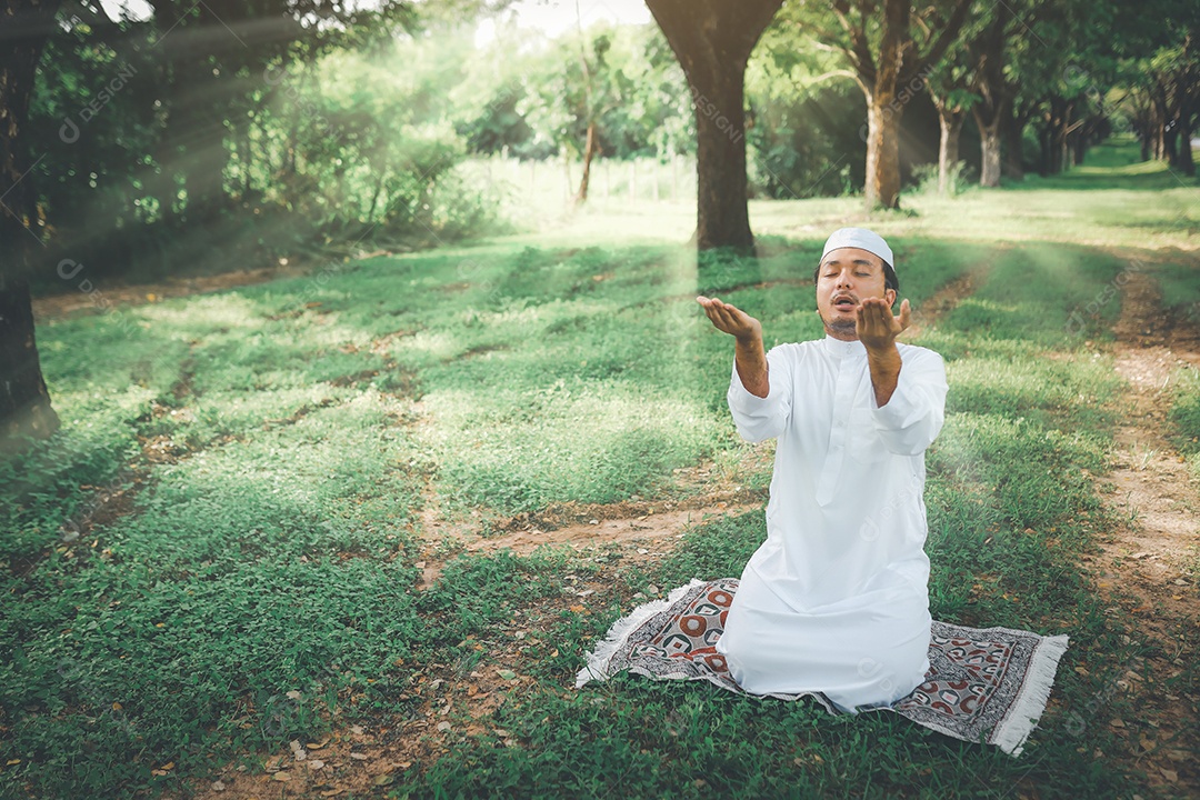 Homem muçulmano religioso tradicional kandura orando ao ar livre em raios de sol de ambiente de natureza tranquila.