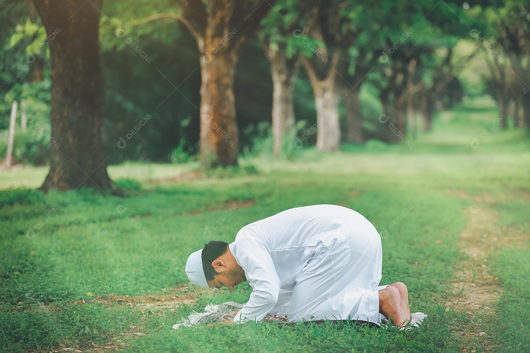 Homem muçulmano religioso tradicional kandura orando ao ar livre em raios de sol de ambiente de natureza tranquila.