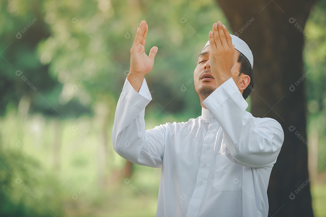 Homem muçulmano religioso tradicional kandura orando ao ar livre em raios de sol de ambiente de natureza tranquila.