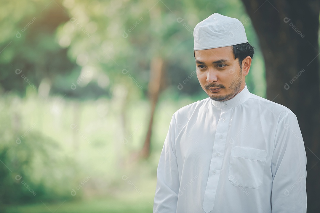 Homem muçulmano religioso tradicional kandura orando ao ar livre em raios de sol de ambiente de natureza tranquila.
