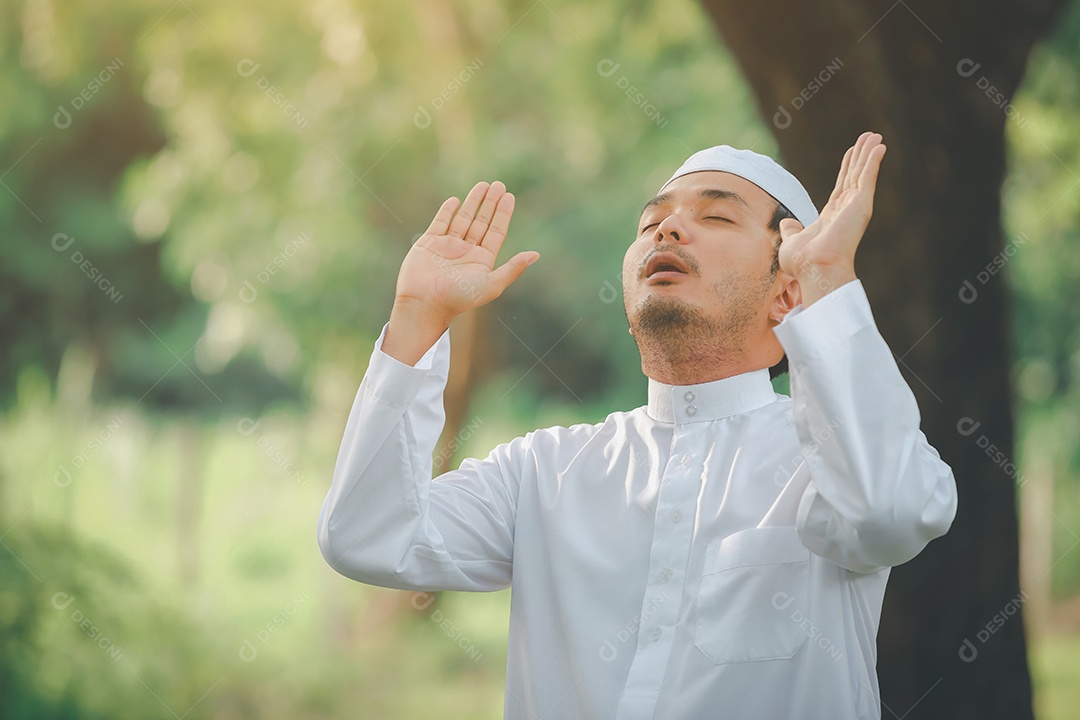 Homem muçulmano religioso tradicional kandura orando ao ar livre em raios de sol de ambiente de natureza tranquila.