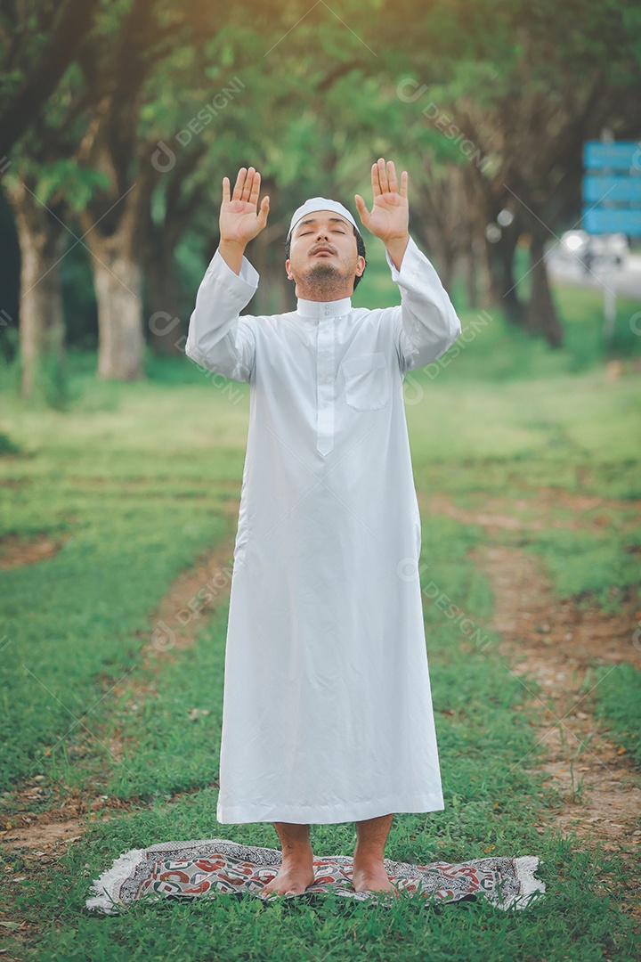 Homem muçulmano religioso tradicional kandura orando ao ar livre em raios de sol de ambiente de natureza tranquila.