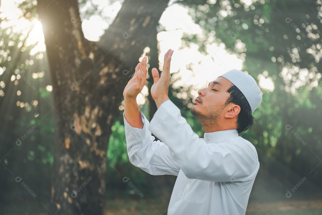 Homem muçulmano religioso tradicional kandura orando ao ar livre em raios de sol de ambiente de natureza tranquila.