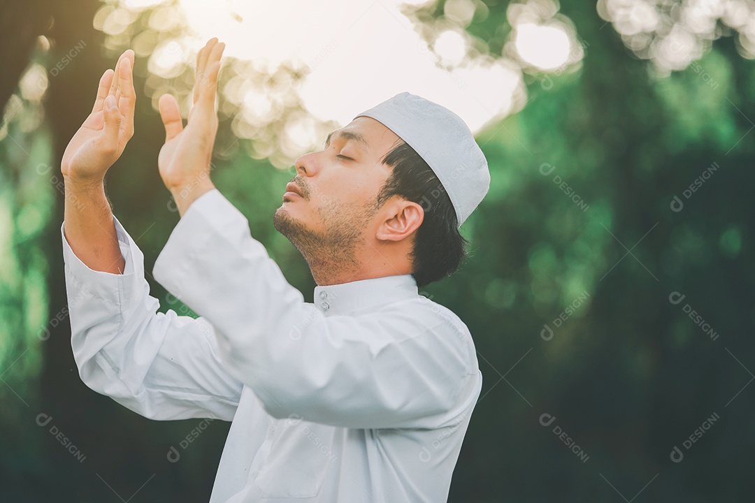 Homem muçulmano religioso tradicional kandura orando ao ar livre em raios de sol de ambiente de natureza tranquila.