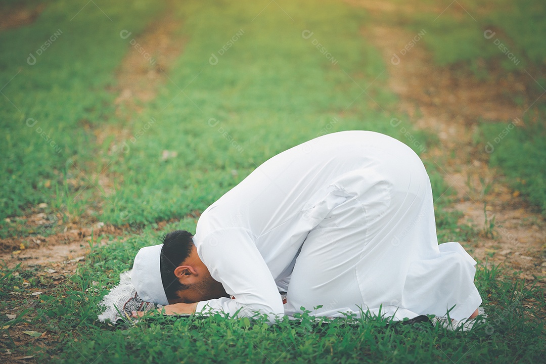 Homem muçulmano religioso tradicional kandura orando ao ar livre em raios de sol de ambiente de natureza tranquila.