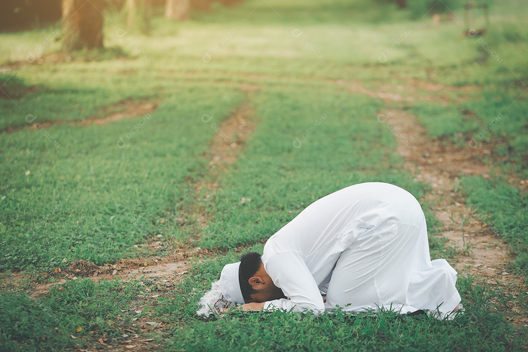 Homem muçulmano religioso tradicional kandura orando ao ar livre em raios de sol de ambiente de natureza tranquila.