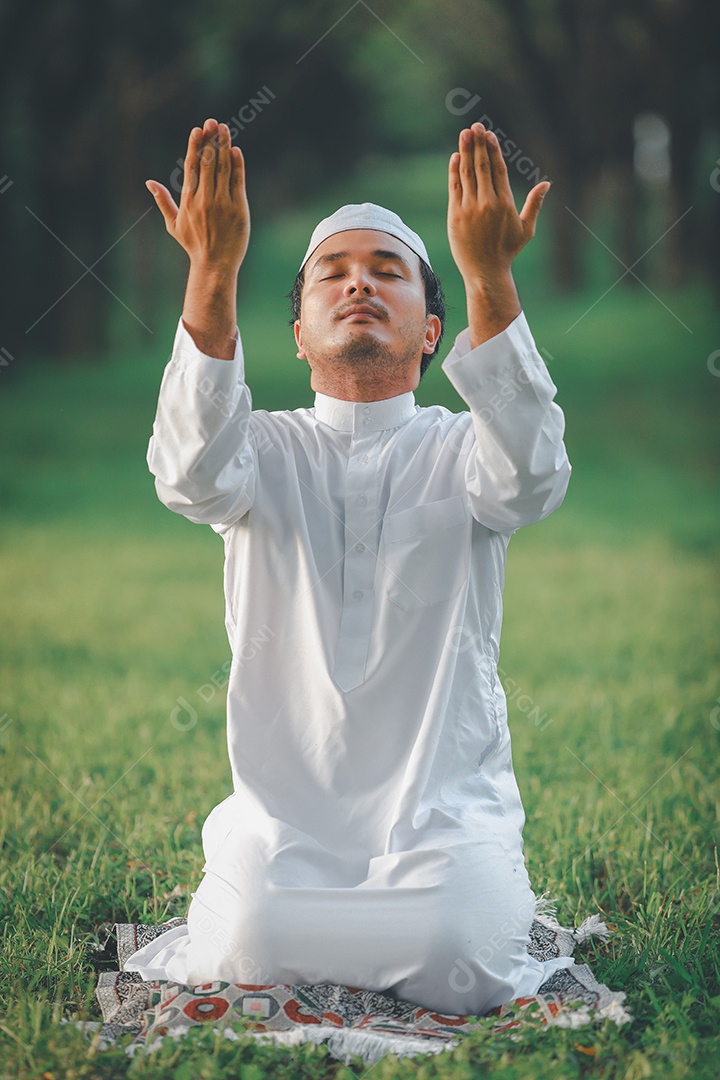 Homem muçulmano religioso tradicional kandura orando ao ar livre em raios de sol de ambiente de natureza tranquila.