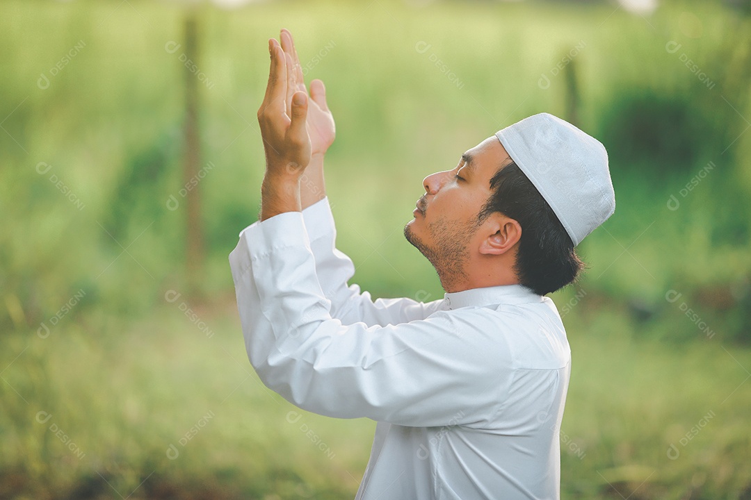 Homem muçulmano religioso tradicional kandura orando ao ar livre em raios de sol de ambiente de natureza tranquila.