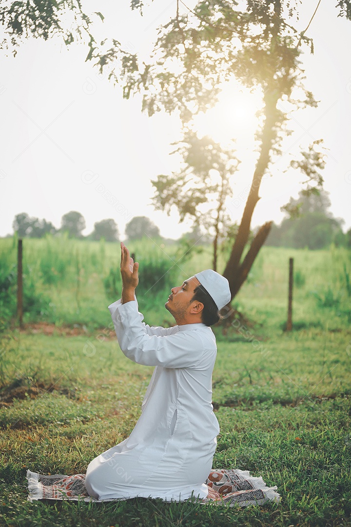 Homem muçulmano religioso tradicional kandura orando ao ar livre em raios de sol de ambiente de natureza tranquila.