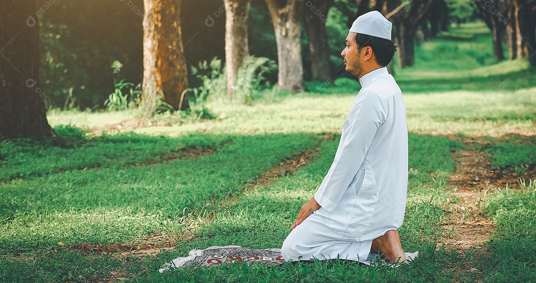 Homem muçulmano religioso tradicional kandura orando ao ar livre em raios de sol de ambiente de natureza tranquila.