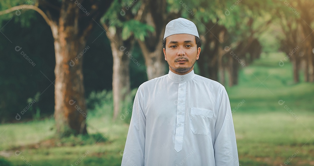 Homem muçulmano religioso tradicional kandura orando ao ar livre em raios de sol de ambiente de natureza tranquila.