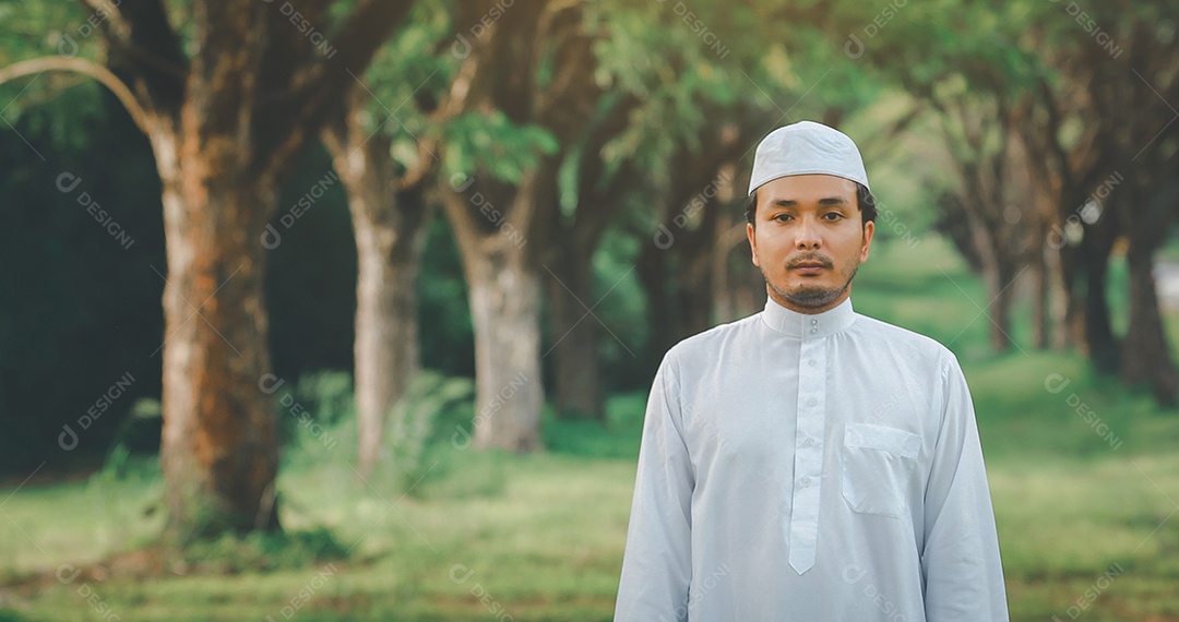 Homem muçulmano religioso tradicional kandura orando ao ar livre em raios de sol de ambiente de natureza tranquila.