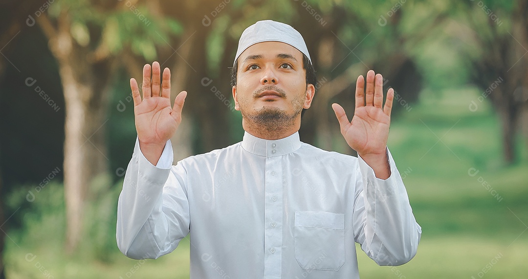 Homem muçulmano religioso tradicional kandura orando ao ar livre em raios de sol de ambiente de natureza tranquila.