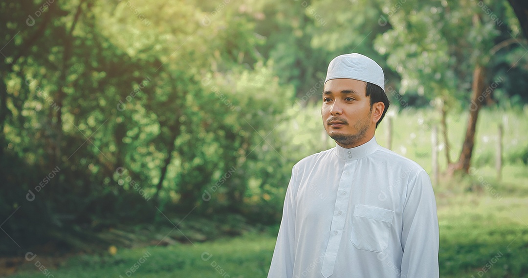 Homem muçulmano religioso tradicional kandura orando ao ar livre em raios de sol de ambiente de natureza tranquila.