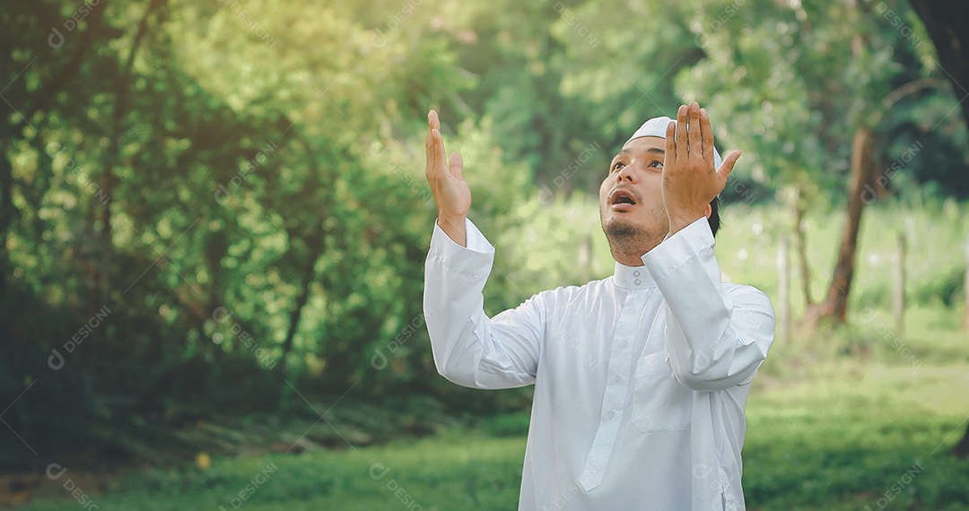 Homem muçulmano religioso tradicional kandura orando ao ar livre em raios de sol de ambiente de natureza tranquila.