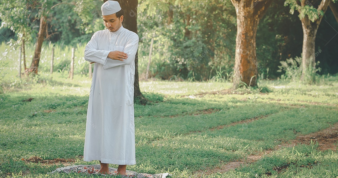 Traditional kandura religious muslim man praying outdoor in tranquil nature environment sun rays.