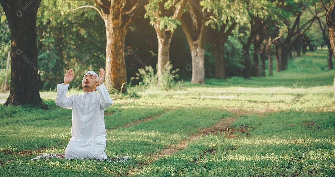 Homem muçulmano religioso tradicional kandura orando ao ar livre em raios de sol de ambiente de natureza tranquila.