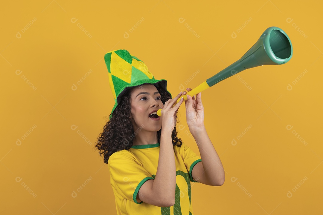 Mulher jovem usando camiseta da seleção brasileira futebol cabelo cacheado sobre fundo amarelo