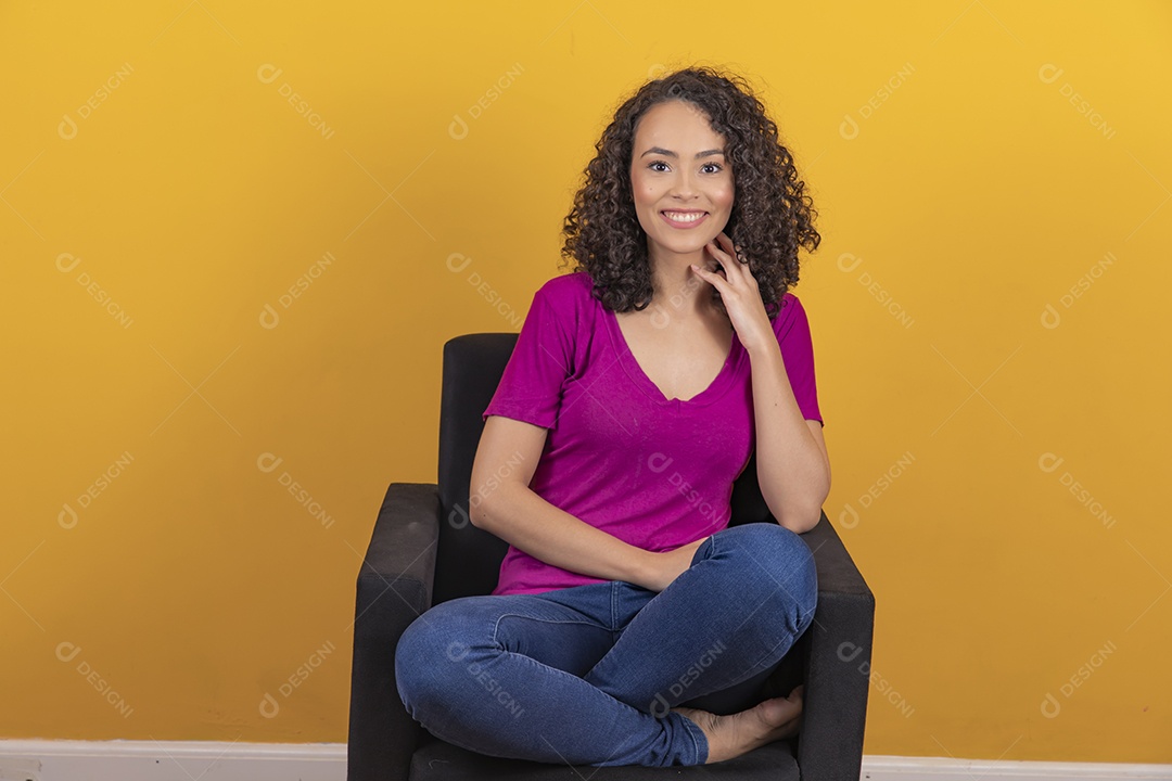 Mulher jovem cabelo cacheado sobre fundo amarelo