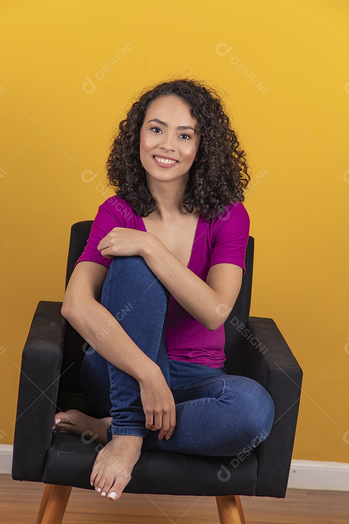 Mulher jovem cabelo cacheado sobre fundo amarelo
