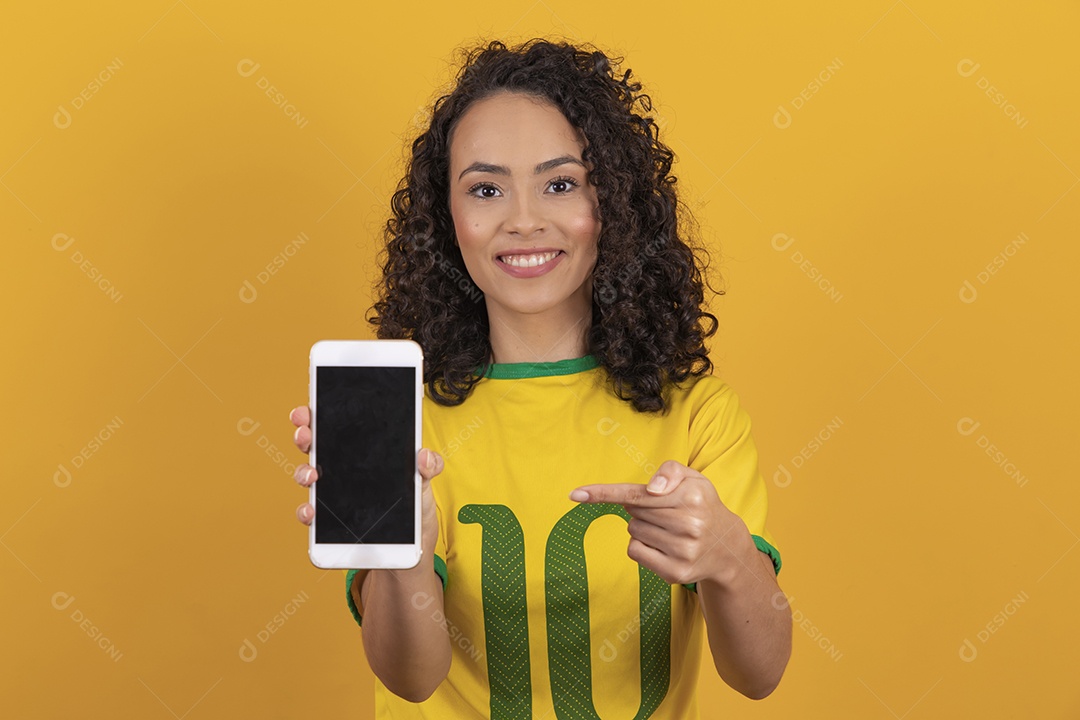 Mulher jovem usando camiseta da seleção brasileira futebol cabelo cacheado sobre fundo amarelo