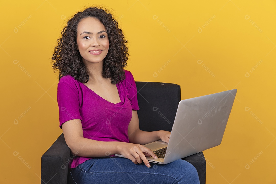 Mulher jovem cabelo mexendo notebook cacheado sobre fundo amarelo