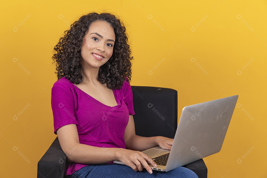 Mulher jovem cabelo mexendo notebook cacheado sobre fundo amarelo