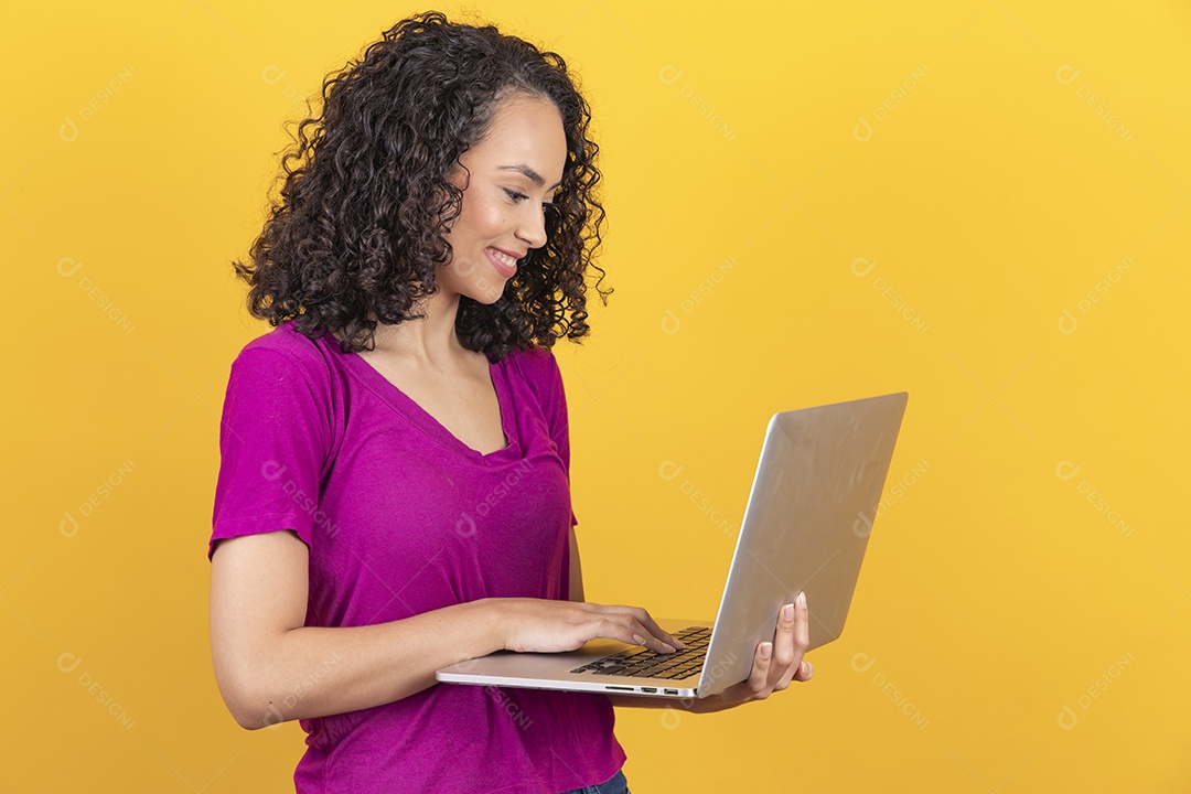 Mulher jovem cabelo mexendo notebook cacheado sobre fundo amarelo