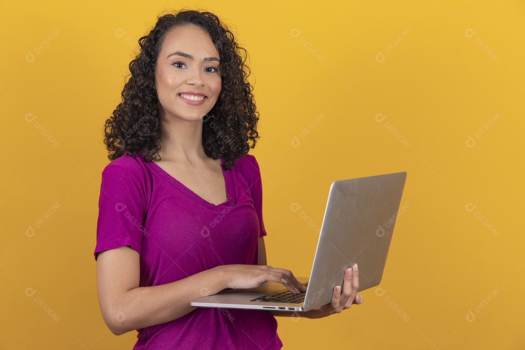 Mulher jovem cabelo mexendo notebook cacheado sobre fundo amarelo