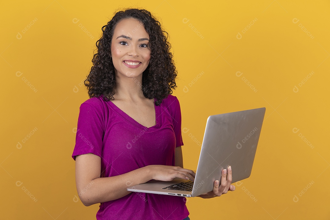 Mulher jovem cabelo mexendo notebook cacheado sobre fundo amarelo