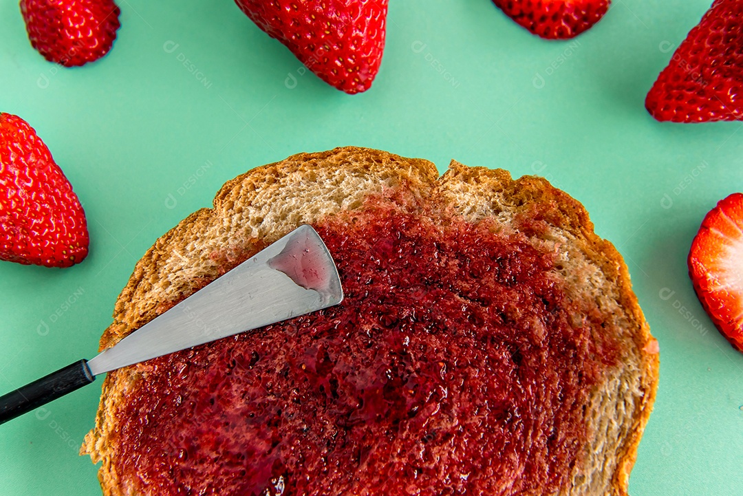 Pão com geleia de morango e morangos em um fundo verde