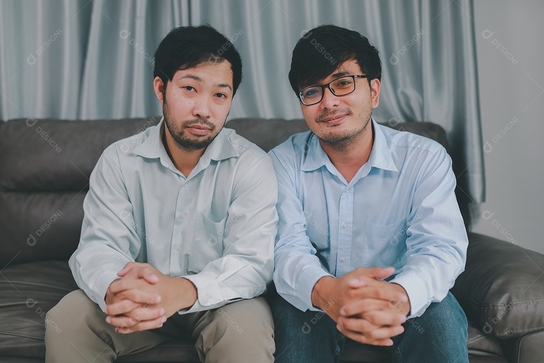 Feliz casal masculino homossexual passando tempo juntos em sofás dentro de suas casas. Feliz juntos conceito.