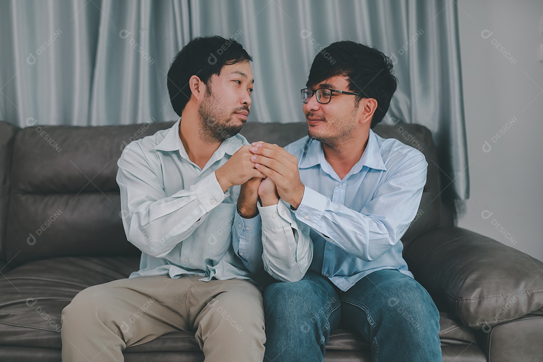 Feliz casal masculino homossexual passando tempo juntos em sofás dentro de suas casas. Feliz juntos conceito.
