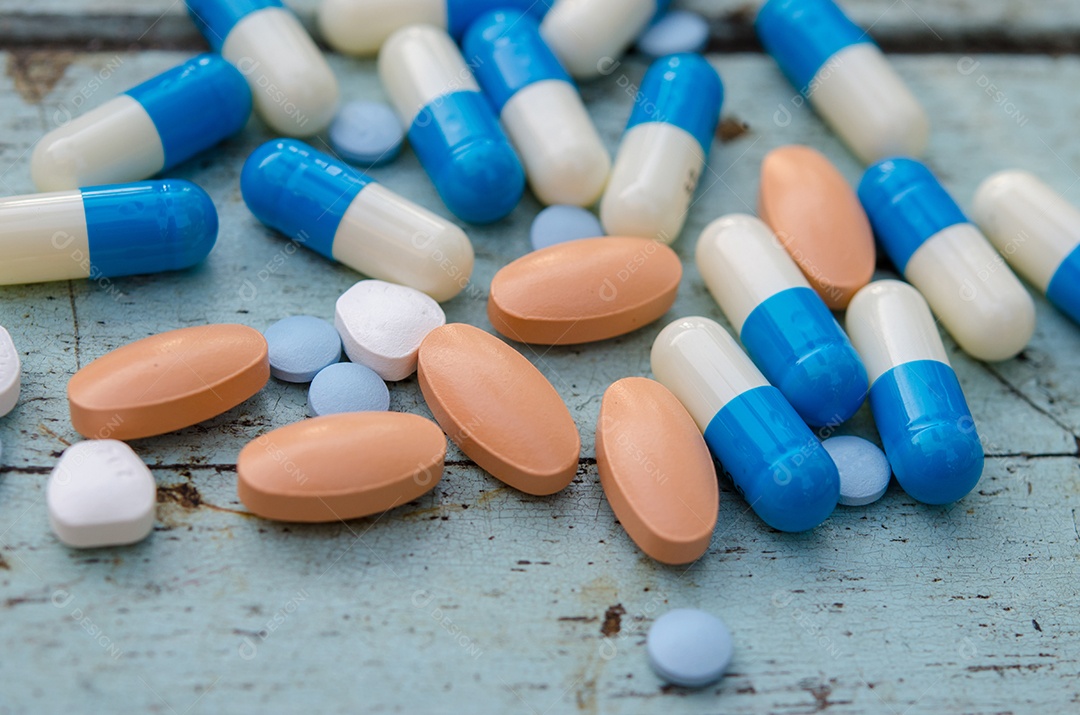 Comprimidos e cápsulas no chão de madeira.