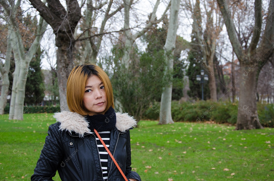 Mulher asiática vestindo um casaco de inverno em pé no jardim.