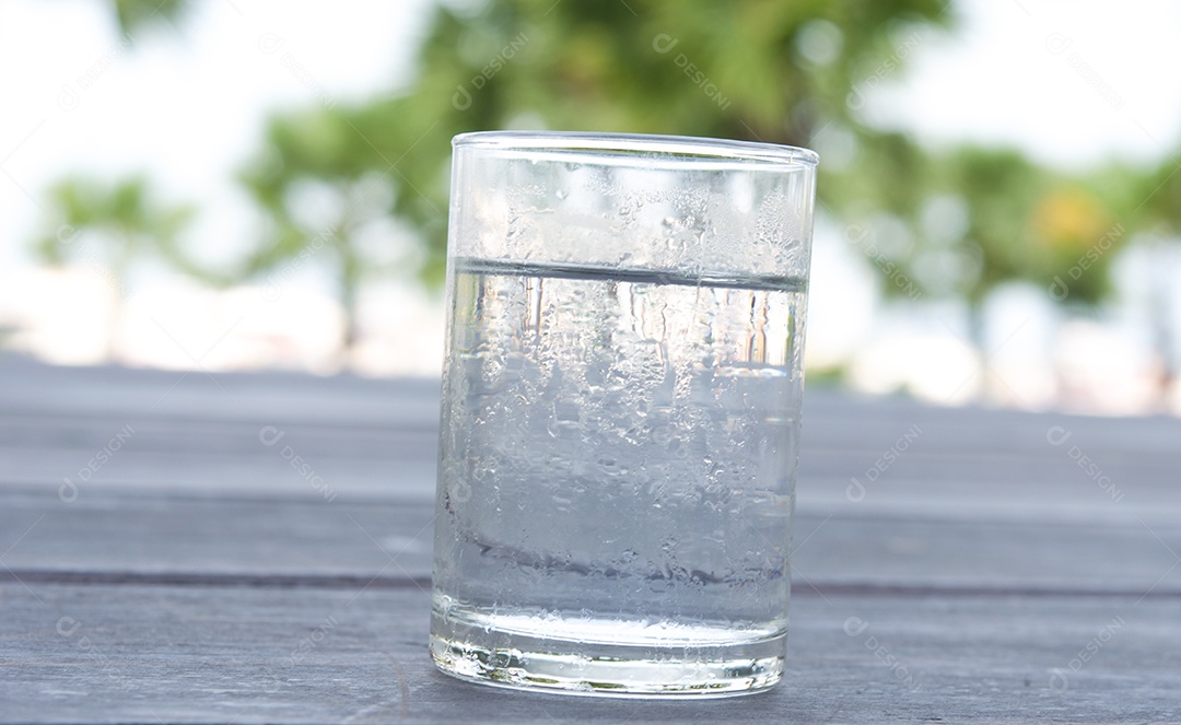 Copo de água colocado em um piso de madeira.