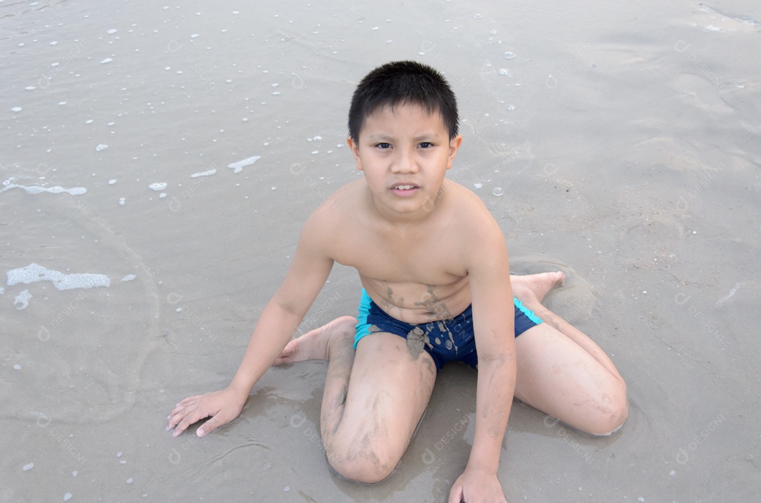 Menino brincando na areia da praia.