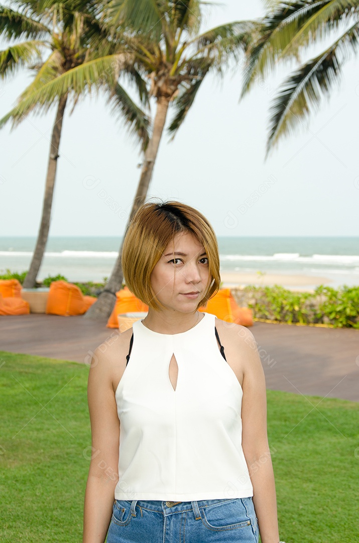 Mulher asiática vestindo camisa branca em pé no jardim.