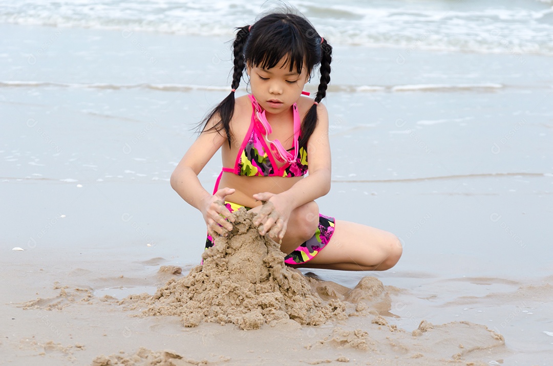 Garota brincando na areia da praia.