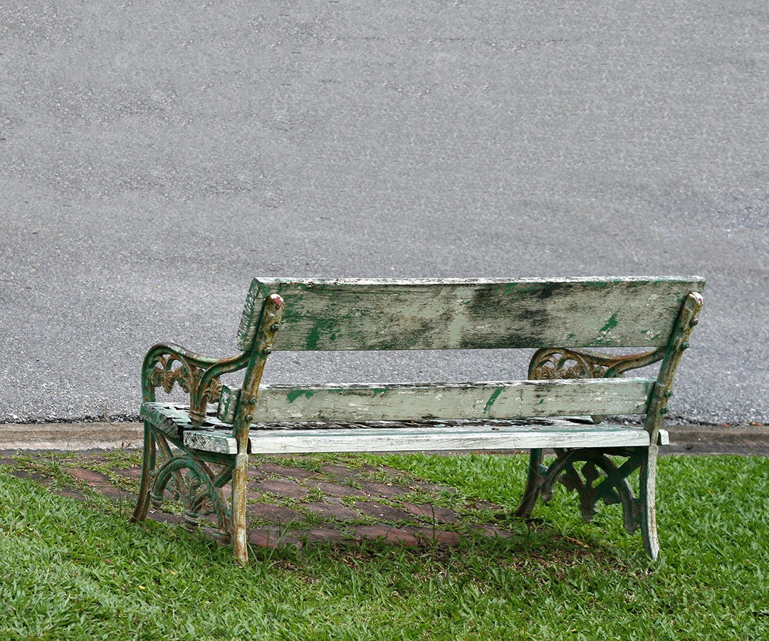 Cadeira de banco de parque de madeira na grama verde no jardim público