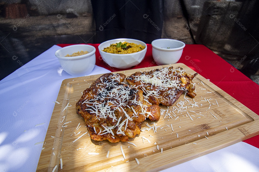Carne assada suculenta com queijo servida em um prato branco com acompanhamentos